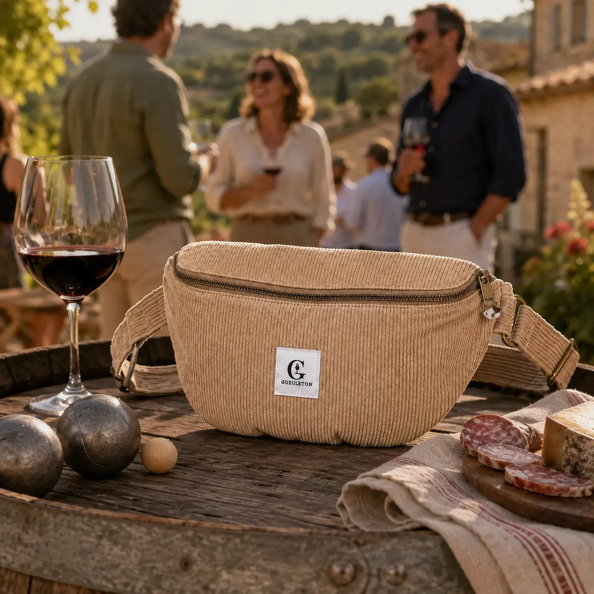Sac banane Gueuleton en velours côtelé beige sur un tonneau, apéro entre amis et boules de pétanque