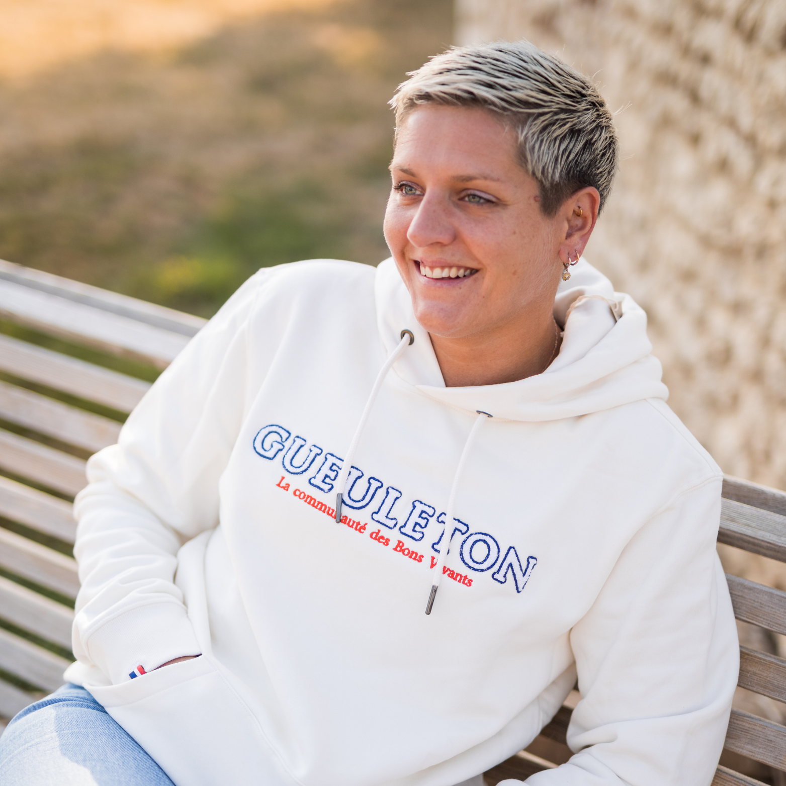 Sweat à capuche Gueuleton unisex Ivory porté par une femme en extérieur - Gueuleton