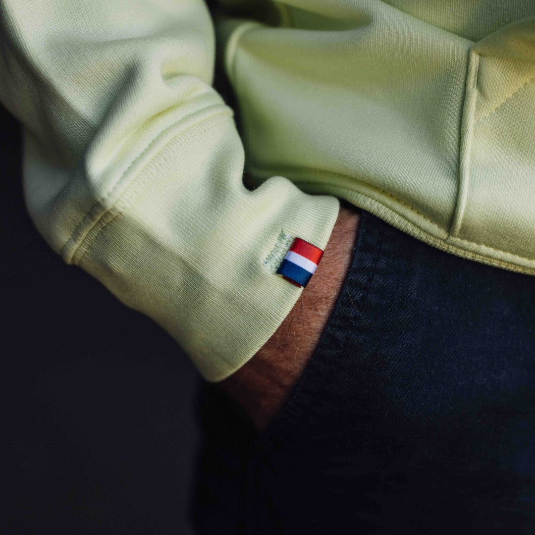 Poignet du sweat à capuche jaune Gueuleton avec un détail du drapeau tricolore français cousu.