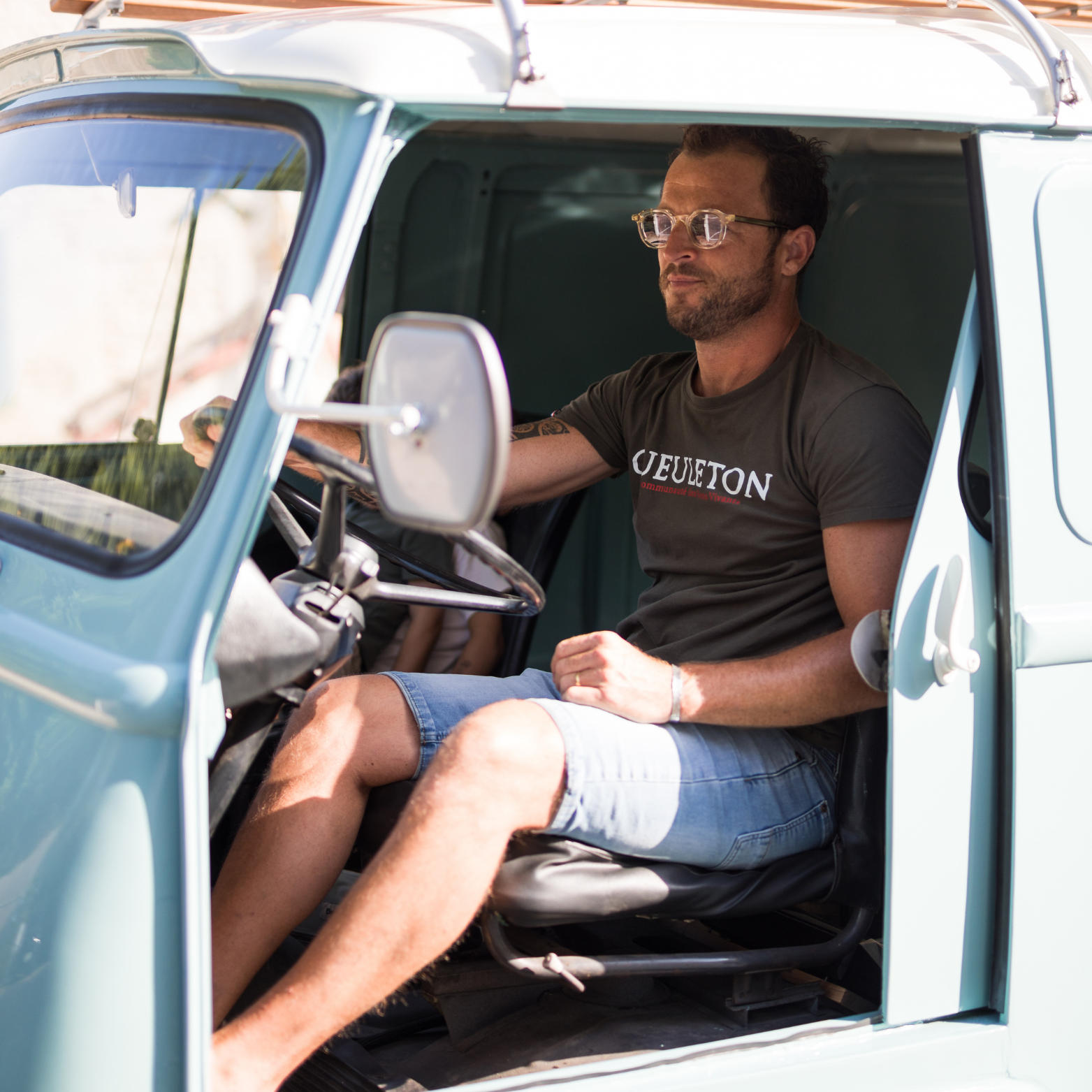 T-shirt Gueuleton Vert Kaki porté par un homme dans un camion vintage - Gueuleton