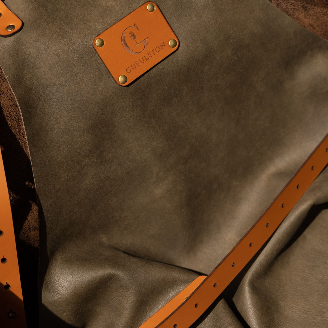 Comparatif des deux tabliers en cuir Gueuleton : modèle Brun et modèle Camel suspendus côte à côte