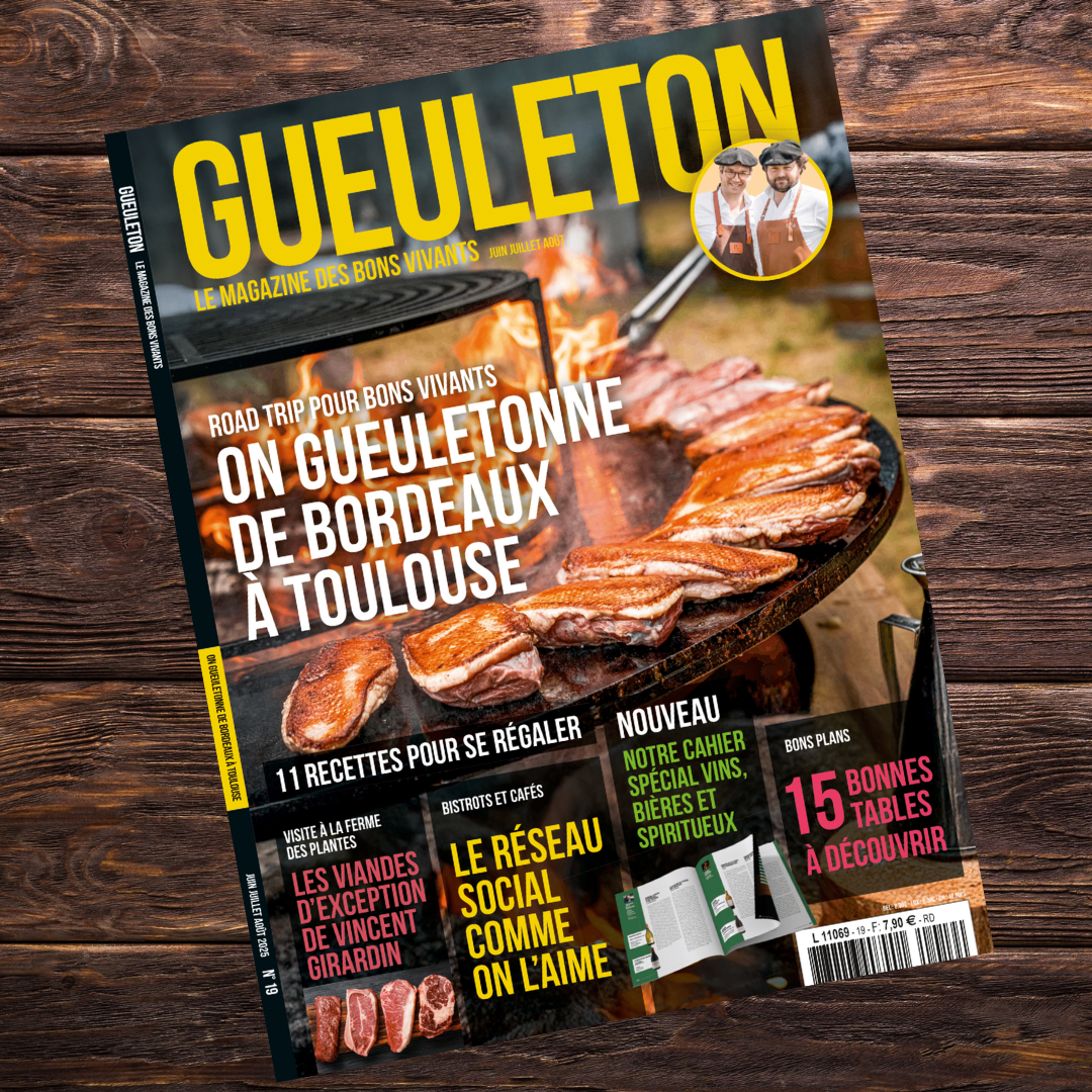 Couverture du magazine Gueuleton n°19 – Été 2025. On y voit une plancha au feu de bois avec des côtes de bœuf grillées. En arrière-plan, les flammes crépitent. En haut à droite, un médaillon avec deux hommes en tablier et béret sourient. Titres visibles : "On Gueuletonne de Bordeaux à Toulouse", "11 recettes pour se régaler", "Les viandes d’exception de Vincent Girardin", "Le réseau social comme on l’aime", "15 bonnes tables à découvrir", etc.

