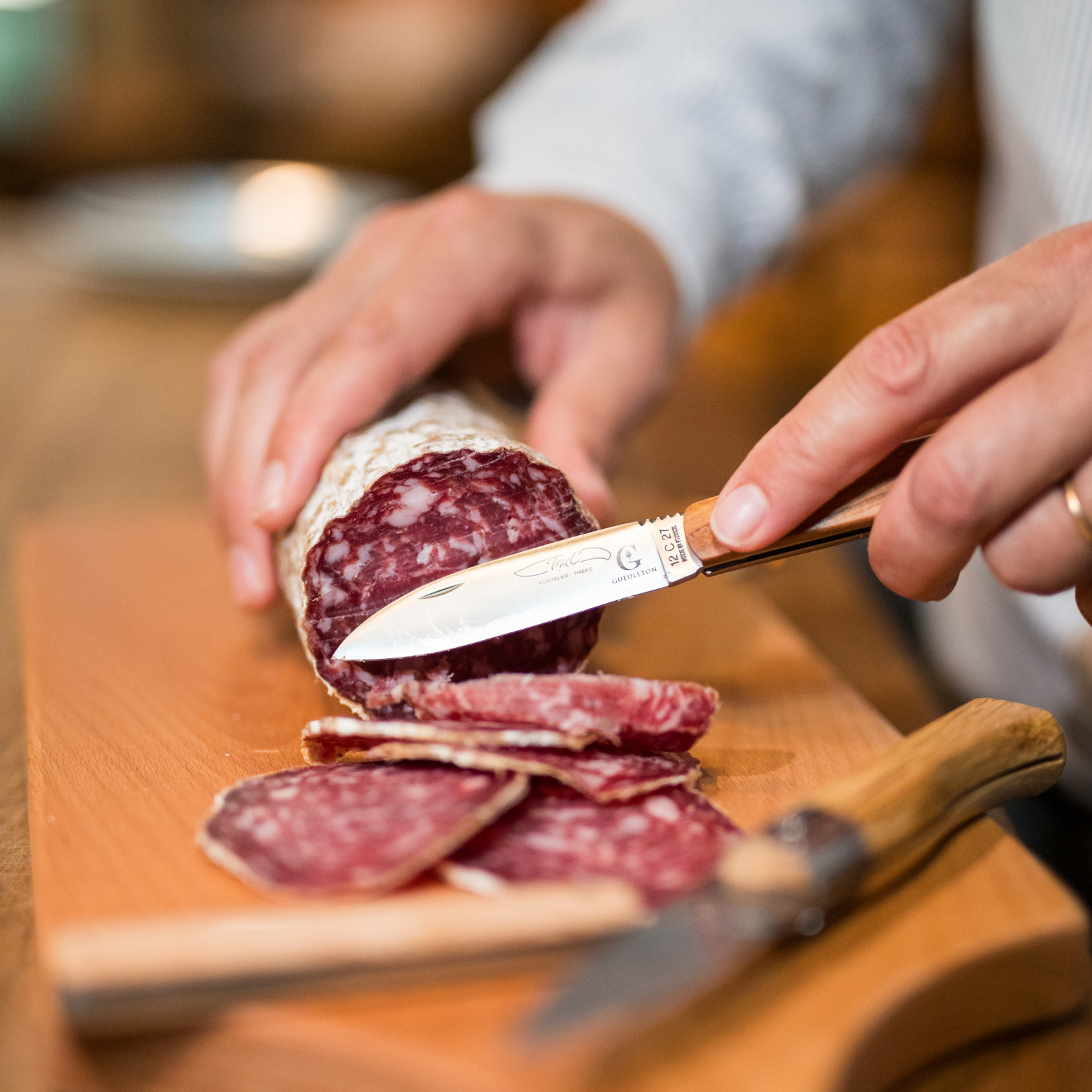 Couteau pliant Gueuleton TMC Herval manche amandier utilisé pour couper du saucisson sur planche bois - Gueuleton