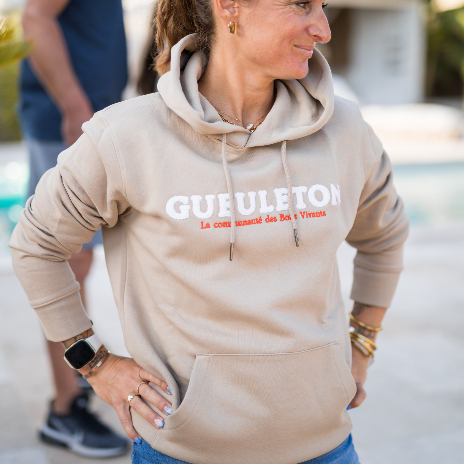 Sweat à capuche Gueuleton unisex Beige porté par une femme en extérieur - Gueuleton