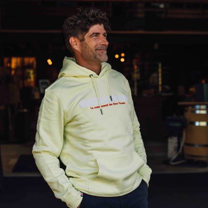 homme portant un sweat à capuche jaune Gueuleton avec le logo 'La communauté des Bons Vivants', style décontracté et convivial