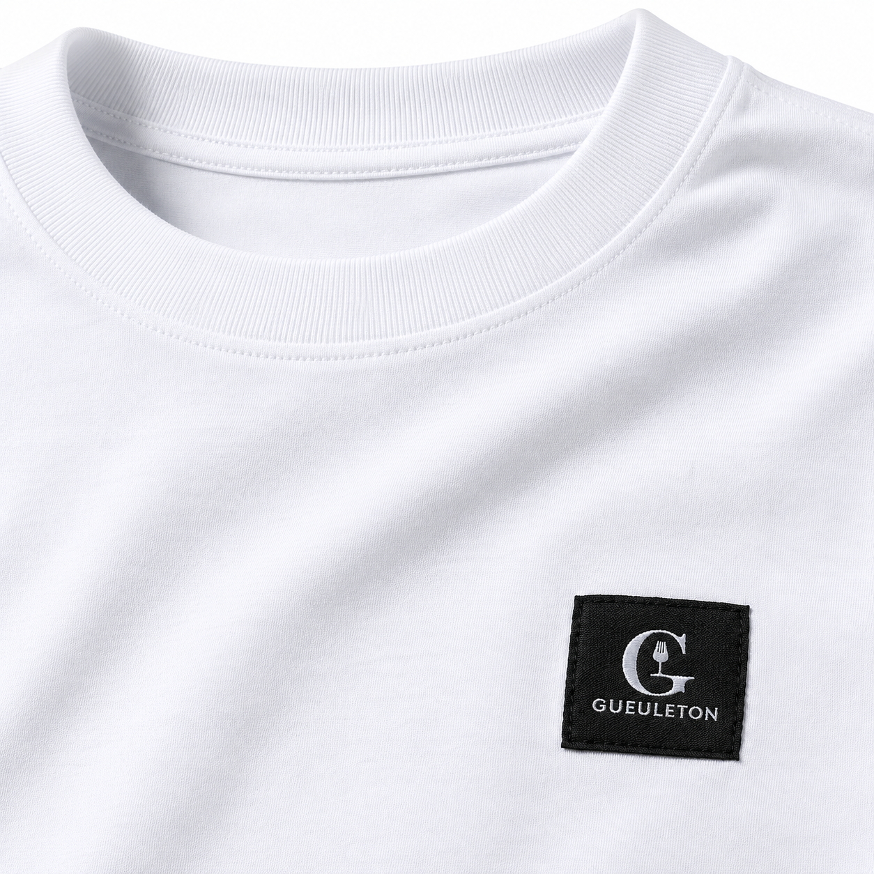 Gros plan patch tissé Gueuleton sur t-shirt blanc coton bio 180g, col rond