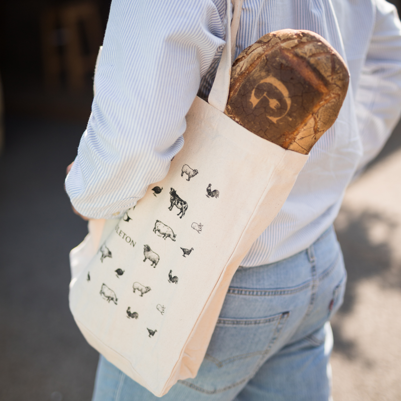 Tote bag Gueuleton porté avec pain artisanal Arthur à l'intérieur - Gueuleton